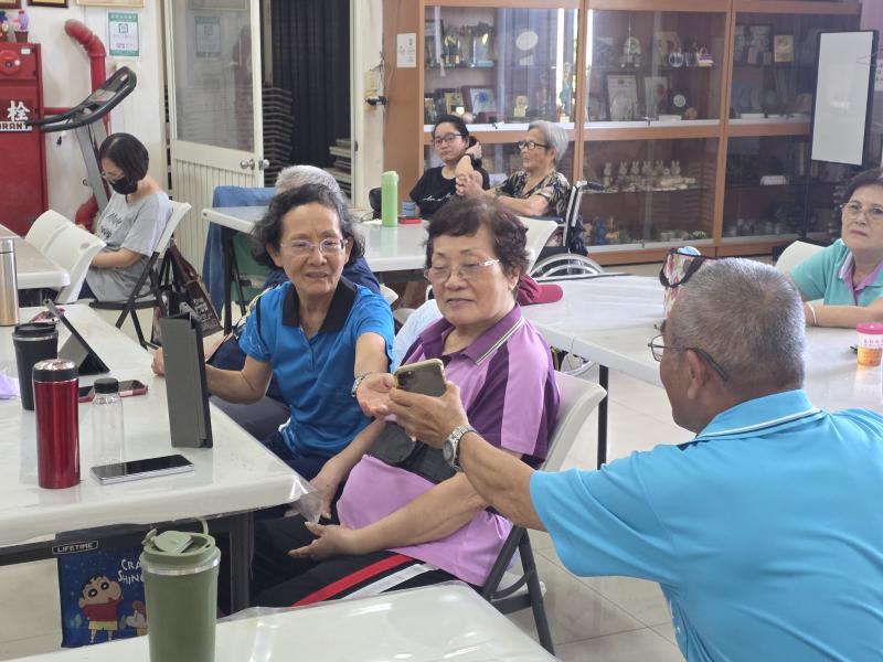 樂齡學員在課堂上熱烈討論，互相展示與分享彼此手機及平板螢幕上的照片作品。